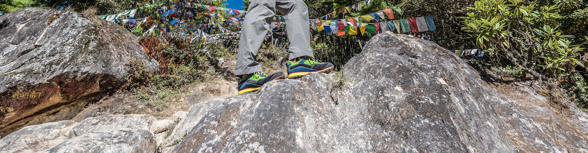 Person wearing AKU shoes with colored flags behind them.